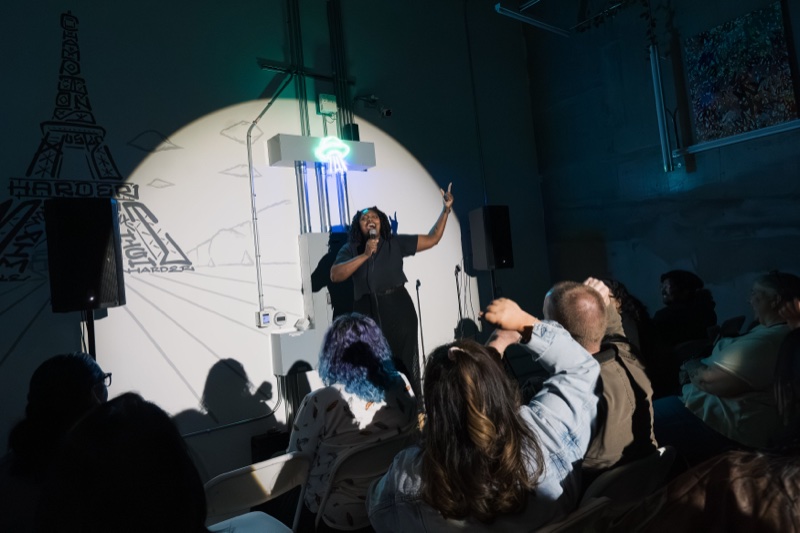 Comedian on stage with raised arm performing at Spaced Out Comedy San Jose